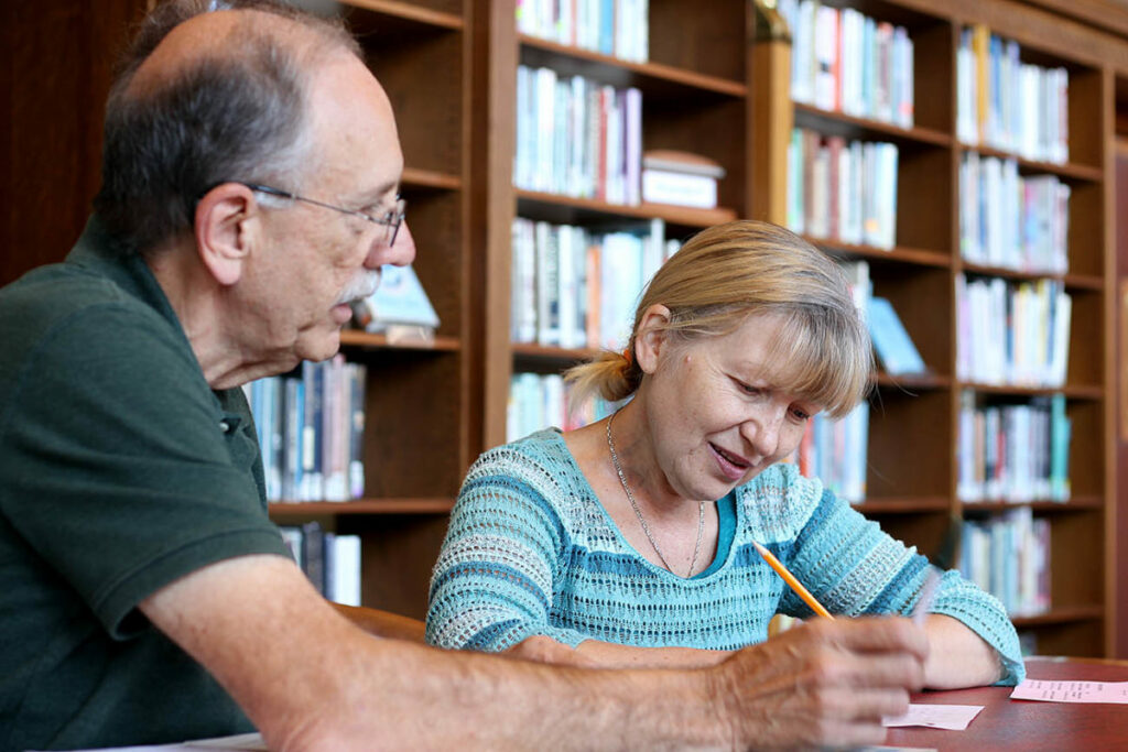 An instructor and a student sitting at a table reviewing papers and writing.