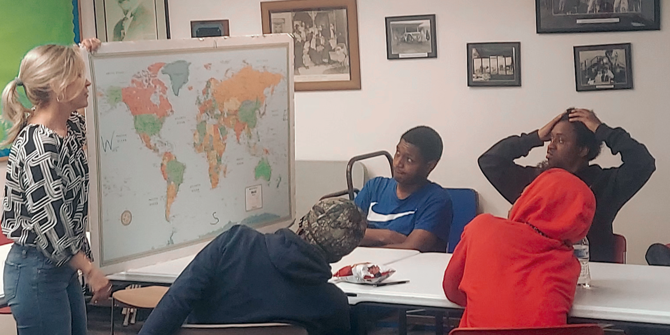 HSE students in a classroom look at a map of the world