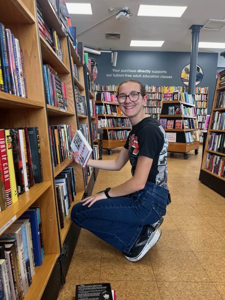 A volunteer kneels to shelve books in the Indy Reads community bookstore