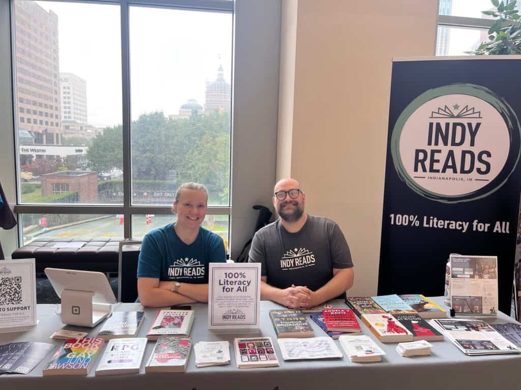 Two volunteers staff an Indy Reads outreach table at a community event